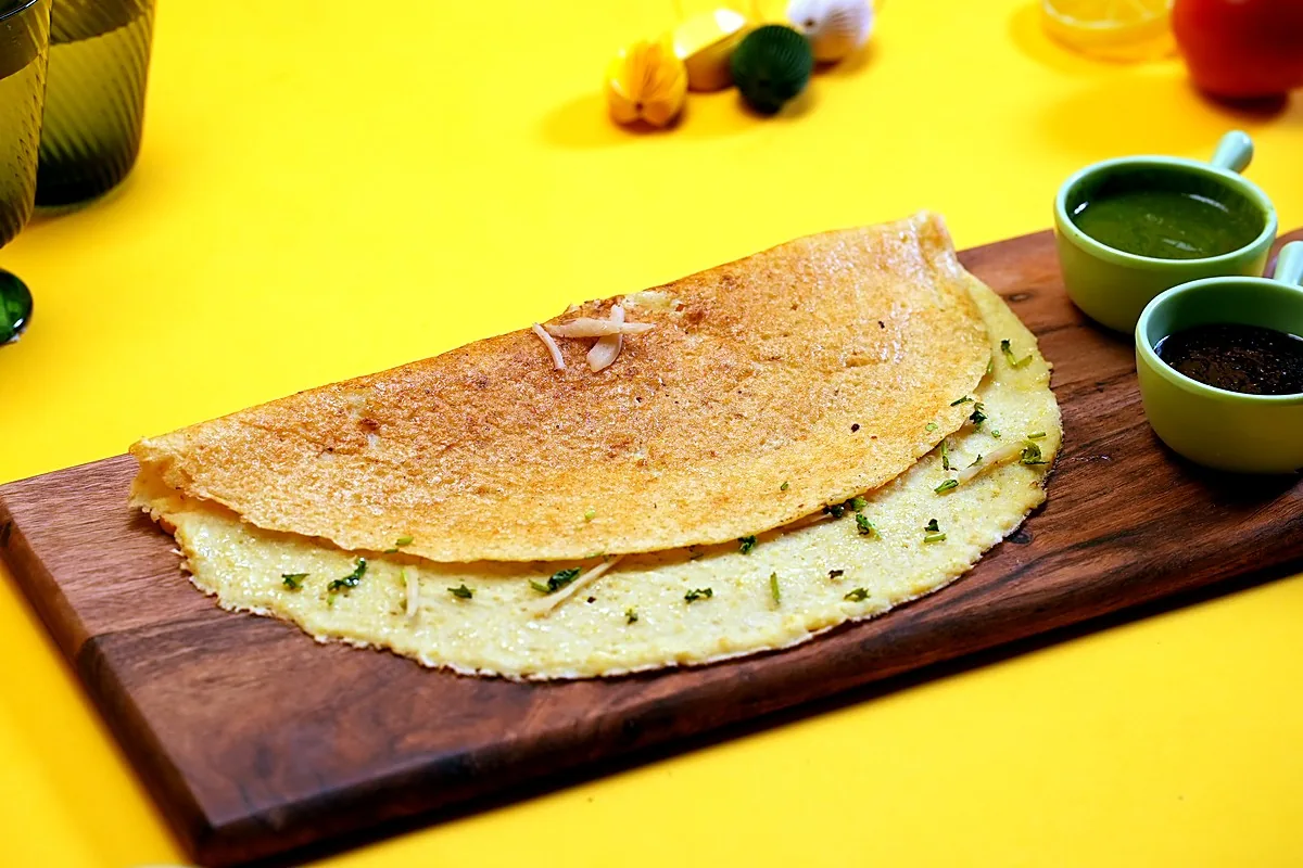 Plain Moong Cheela on a wooden board with two chutneys