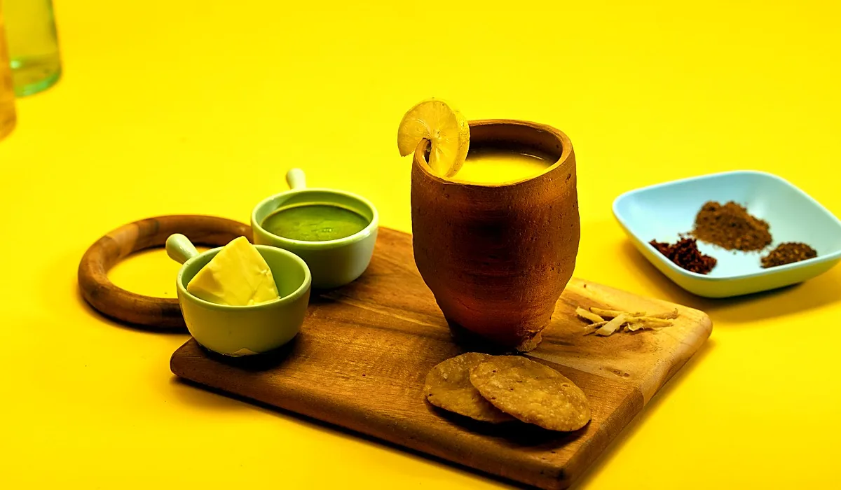 Dal Muradabadi in a clay kulhad on a wooden board, with chutneys and crisps